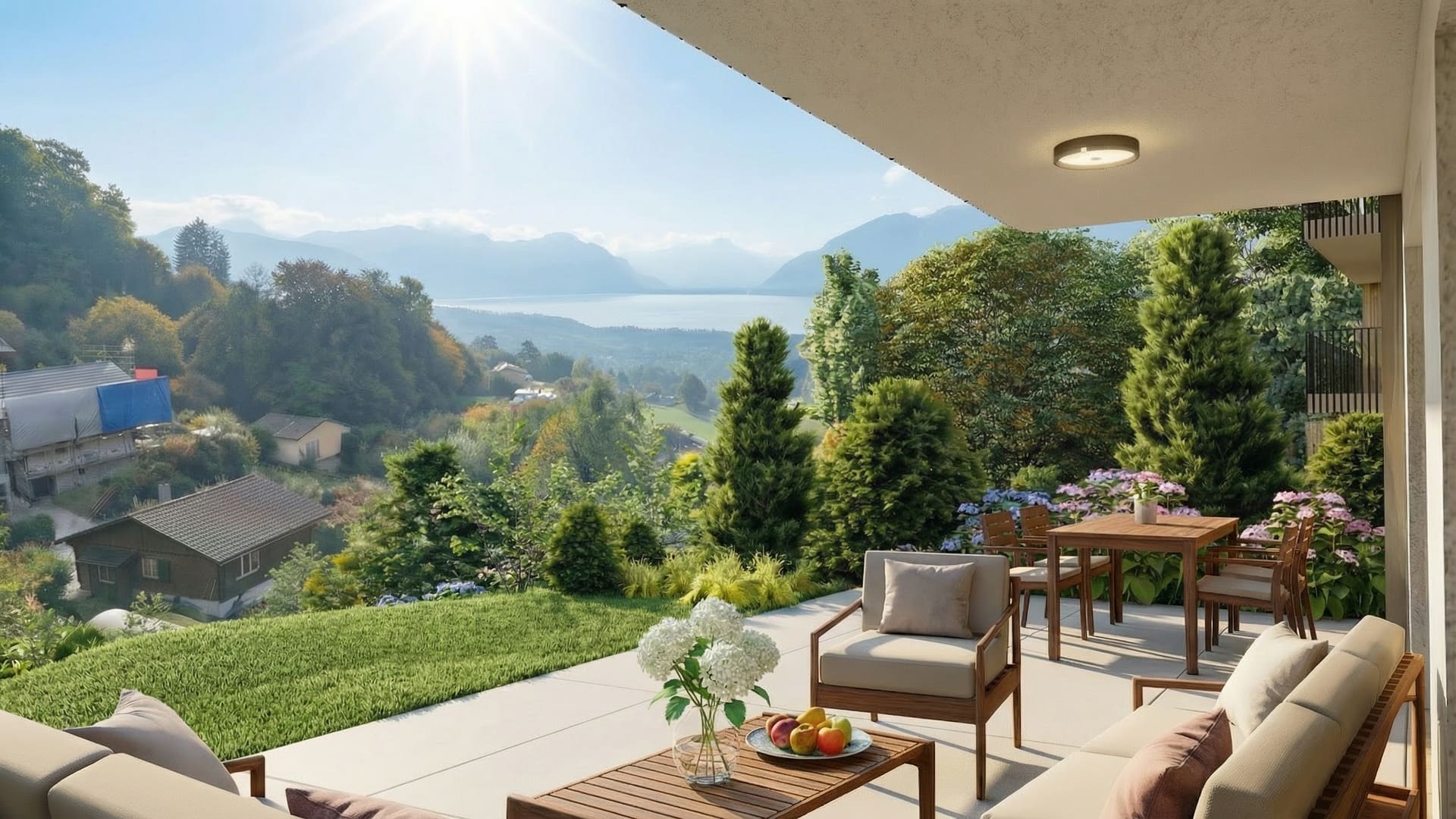 Terrasse couverte avec salon et table à manger en bois, dallage clair, jardin paysager et vue dégagée sur le lac et les montagnes.